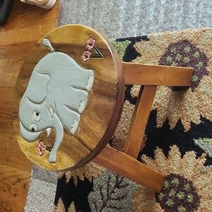 a small wooden foot stool with an elephant print on the top.